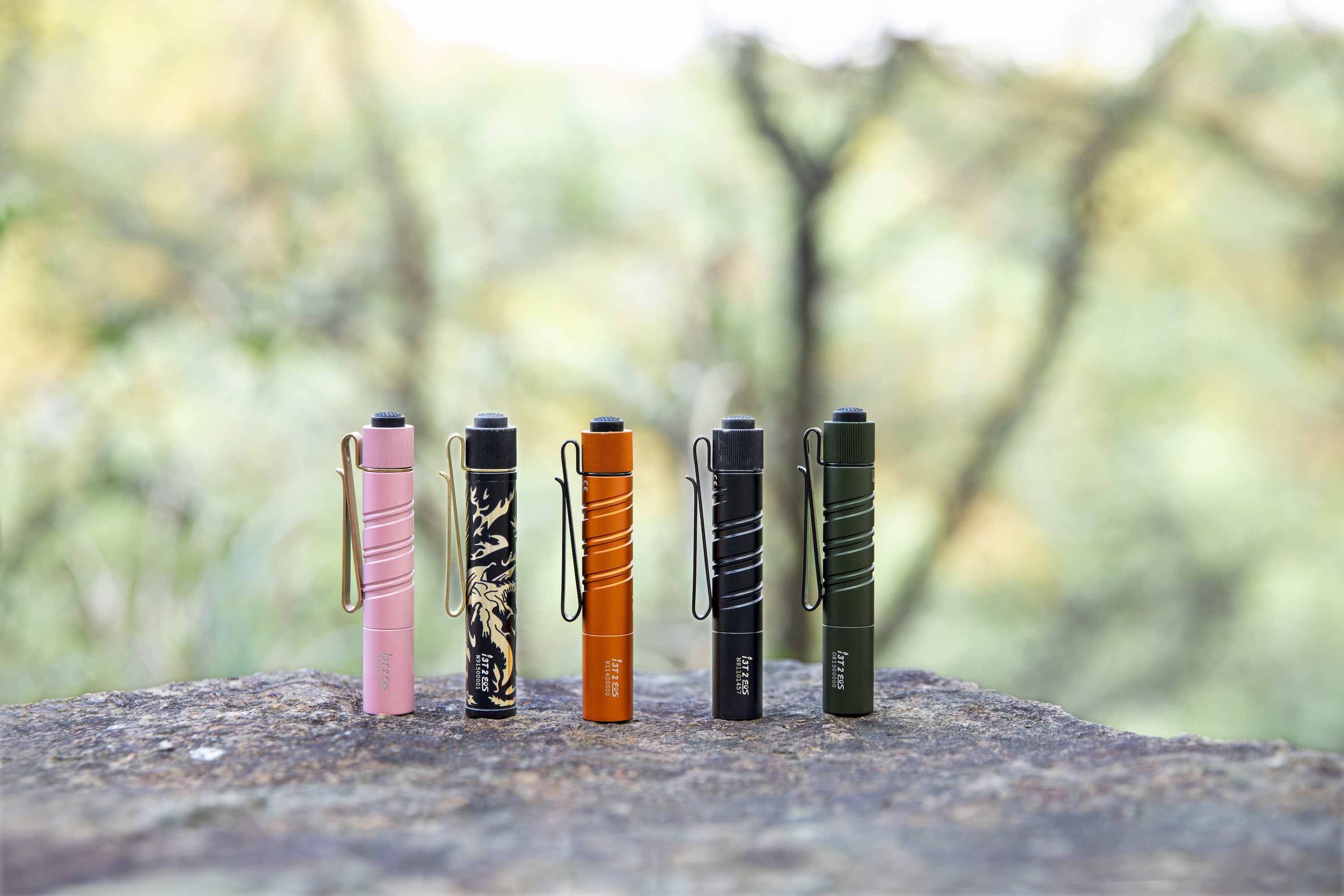 Mehrere Olight i3T 2 Farbvarianten nebeneinander auf einem Stein