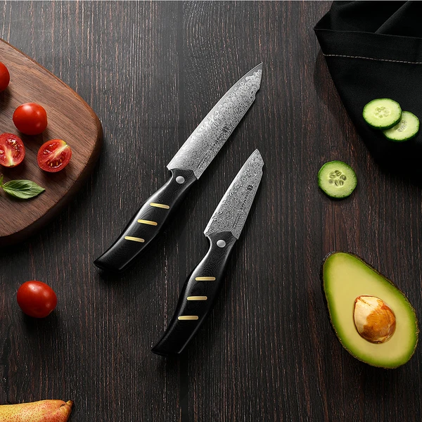 Hochwertige Damastmesser mit frischem Gemüse auf dunklem Holzbrett.