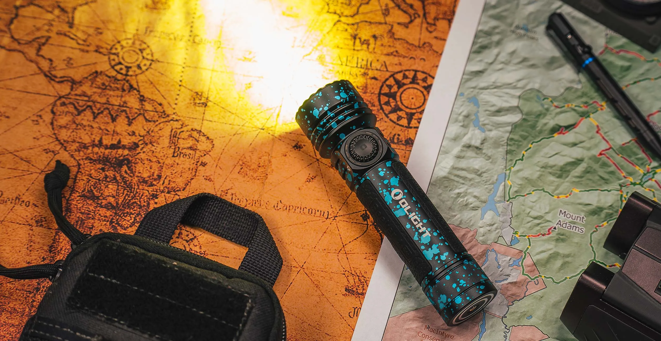 Olight Seeker 4 Pro neben Karten und Outdoor-Ausr&uuml;stung