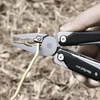 NexTool W40 Multitool-Zange schneidet ein gelbes Kabel im Freien