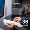 Hände legen Akku in Computerzubehör; Ostation X Ladegerät für 36 Akkus im Hintergrund.
