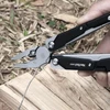 NexTool W40 Multitool-Zange schneidet Metalldraht im Freien über Holzuntergrund