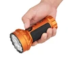 Hand hält leuchtstarke orangefarbene Olight Marauder Mini LED-Taschenlampe mit schwarzen Griffen und runden Linsen