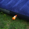 Olight orange MAX PUMP 3 zum Aufblasen einer blauen Luftmatratze auf Gras für Camping und Outdoor-Aktivitäten.