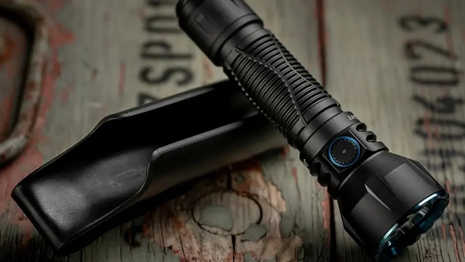 Schwarze taktische LED-Taschenlampe mit blauem Ring und Holster auf Holz.