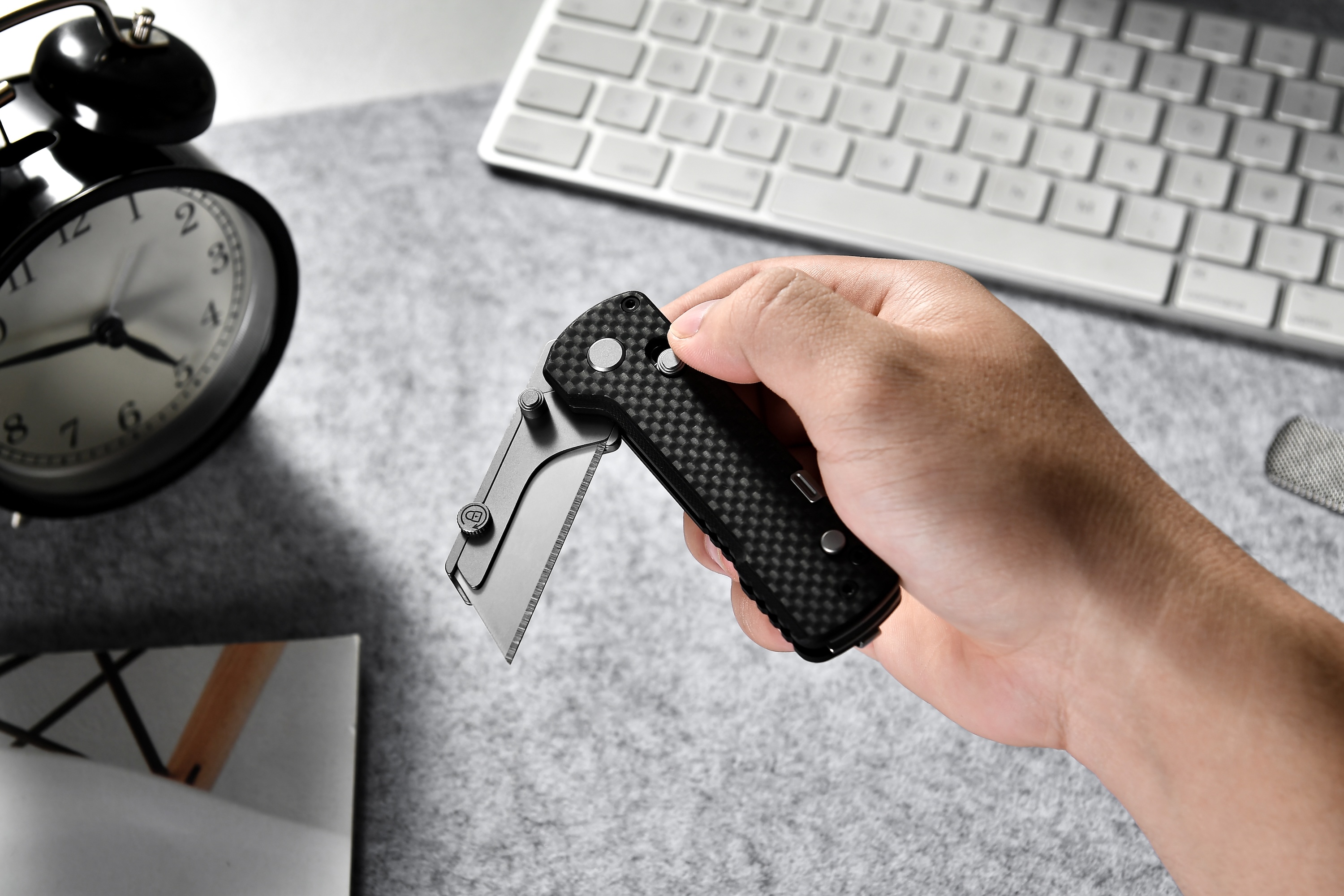 Olight U1 Pro mit Carbonfasergriff wird am Schreibtisch in der Hand gehalten