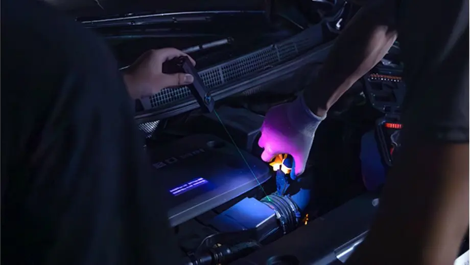 Automotorprüfung bei Dunkelheit mit UV-Lampe und Laser zur Leckfindung.