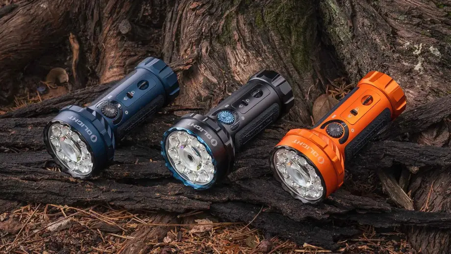 Drei blaue, schwarze, orange Olight Taschenlampen auf Waldholz.