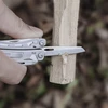 Multitool-Messer schnitzt trockenes Holz beim Bushcrafting im Wald