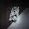 NexTool Multitool zusammengeklappt auf dunklem Holz mit leuchtendem grünen Detail