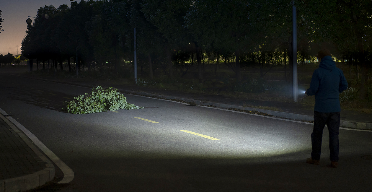 Erwachsene Person leuchtet mit Olight iUltra EOS einen dunklen Weg aus