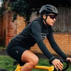 Rennradfahrerin mit schwarzem Helm, Sportbrille und dhb-Radhose fährt auf einem gelben Rennrad.